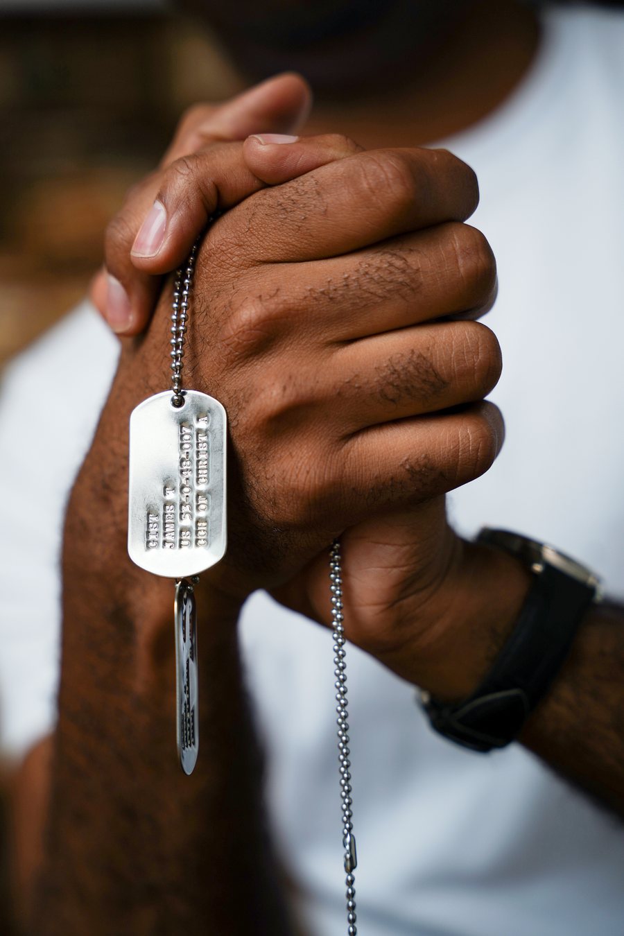 Detail of hands holding dog tags on a chain